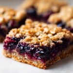 Close-up of a delicious Blueberry Crumble Bar showing the thick blueberry filling and oat crumble topping.