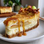 A close-up of a slice of Caramel Apple Cheesecake Bars, drizzled with caramel sauce and layered with apple slices.