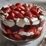 Close-up of a Chocolate Covered Strawberry Trifle in a glass bowl, showing layers of chocolate cake, whipped cream, and fresh strawberries.