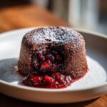 A rich Chocolate Raspberry Lava Cake with a molten raspberry center, dusted with powdered sugar.
