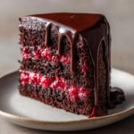 A decadent slice of Chocolate Raspberry Truffle Cake with rich chocolate ganache dripping down the sides.