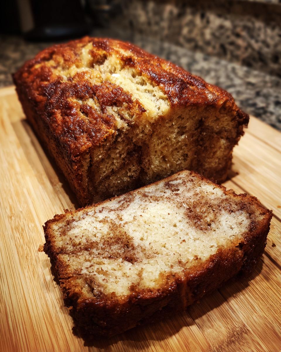 A close-up of a slice of delicious Cinnamon Swirl Banana Bread on a wooden cutting board.