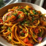 A close-up of a bowl of Creamy Cajun Shrimp Pasta, featuring linguine, shrimp, bell peppers, and red onion, garnished with parsley.