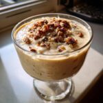 A close-up of a creamy Hazelnut Praline Mousse topped with crunchy praline pieces and chopped hazelnuts.