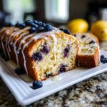 A slice of moist Lemon Blueberry Pound Cake with a sweet glaze and fresh blueberries on top.