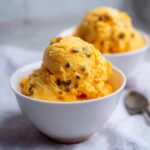 Two bowls of vibrant orange Mango Passionfruit Sorbet, topped with passionfruit seeds.