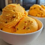 Close-up of two white bowls filled with vibrant orange Mango Passionfruit Sorbet, showing scoops with visible passionfruit seeds.