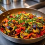 Close-up of Rustic Ratatouille with Fresh Herbs cooked in a pan, featuring eggplant, zucchini, and bell peppers.