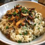 A close-up of creamy Savory Mushroom Risotto topped with sautéed mushrooms and fresh parsley.