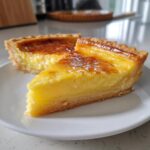A close-up of a slice of perfect vanilla custard tart with a golden-brown, slightly caramelized top.