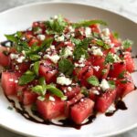 A close-up of a vibrant Watermelon Feta Salad with Mint, drizzled with balsamic glaze.