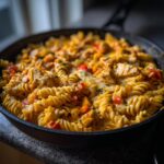 A close-up view of a Cheesy Cajun Chicken Rotini Skillet, showing rotini pasta, chicken pieces, and melted cheese.