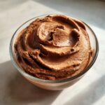 A close-up of creamy chocolate frozen banana ice cream in a glass bowl, swirled to perfection.