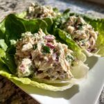 Close-up of fresh Costco chicken salad served in crisp lettuce cups, garnished with parsley and red onion.