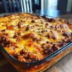 A close-up of a pan of Delicious Easy Ground Beef Enchiladas, bubbling with melted cheese and seasoned beef.