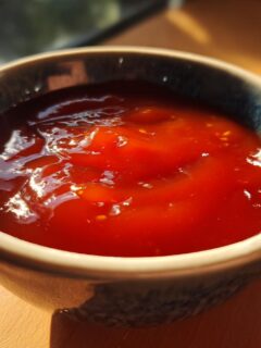 Close-up of a bowl filled with Irresistible Sweet And Sour Sauce, glistening in the light.