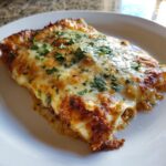 A delicious slice of Irresistible White Chicken Enchiladas, topped with melted cheese and fresh parsley.