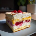 A slice of no-bake pavés dessert with layers of cream, berries, and sponge cake, topped with fresh fruit.