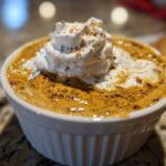 Close-up of creamy Pumpkin Cheesecake Dip topped with whipped cream and a sprinkle of cinnamon.