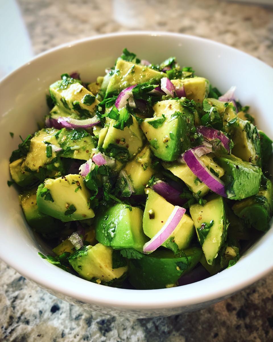 Close-up of a Refreshing Cucumber Avocado Salad with red onion and cilantro in a white bowl.