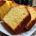 Close-up of moist, golden-brown slices of Slap Ya Momma Pound Cake on a white plate.