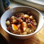 Close-up of a 10 Minute Fall Harvest Quinoa Breakfast Bowl topped with apples, pecans, and syrup.