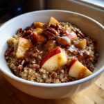 Close-up of a 10 Minute Fall Harvest Quinoa Breakfast Bowl topped with caramelized apples, pecans, and cinnamon.