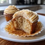 Close-up of The Best Banana Cupcakes Maple Buttercream, showing a bite taken out to reveal the moist crumb and swirled frosting.