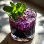 A vibrant purple Blueberry Lavender Chamomile Mocktail garnished with fresh mint and ice.