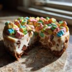 A slice of Chocolate Chip Cheesecake Lucky Charms, topped with colorful marshmallows and chocolate chips.