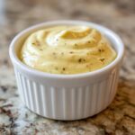 Close-up of thick, yellow Creamy Honey Mustard Dressing Dairy Free swirled in a small white ramekin.