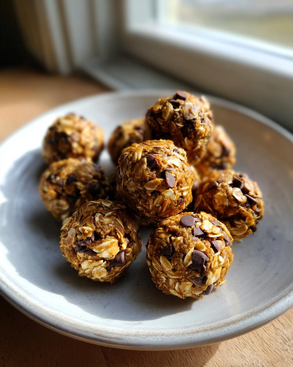 A pile of Easy Healthy Peanut Butter No Bake Energy Bites, studded with oats and chocolate chips, served on a light gray plate.