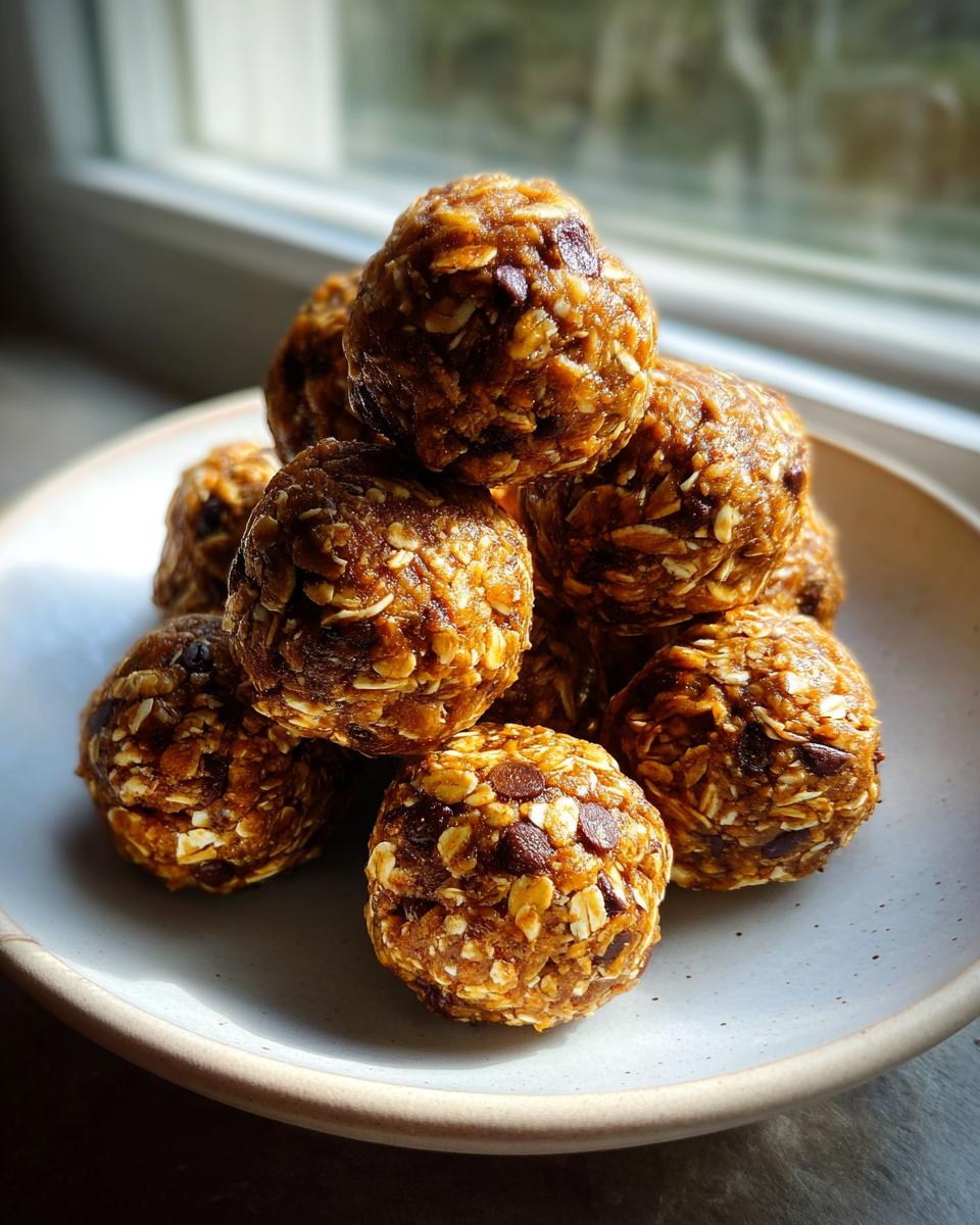 A stack of Easy Healthy Peanut Butter No Bake Energy Bites made with oats and chocolate chips on a light plate.