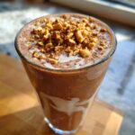 Close-up of an Easy Peanut Butter Chunky Monkey Milkshake topped with chopped peanuts.