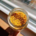 Close-up overhead view of a glass jar filled with vibrant yellow Homemade Lemon Pepper Seasoning.
