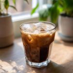 A refreshing Iced Vanilla Latte With Quinoa Milk filled with ice and topped with foam.