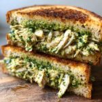 Close-up of an Irresistible Chicken Pesto Sandwich, showing shredded chicken mixed with vibrant pesto between toasted bread.