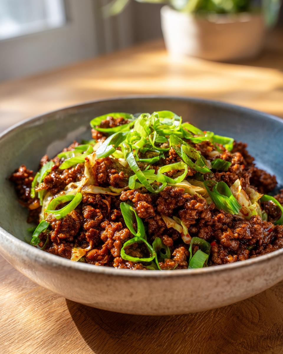 A close-up of Irresistible Egg Roll In A Bowl, featuring savory ground meat and cabbage topped with fresh green onions.