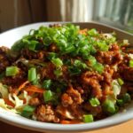 Close-up of a bowl filled with Irresistible Egg Roll In A Bowl, featuring ground meat, shredded cabbage, carrots, and green onions.