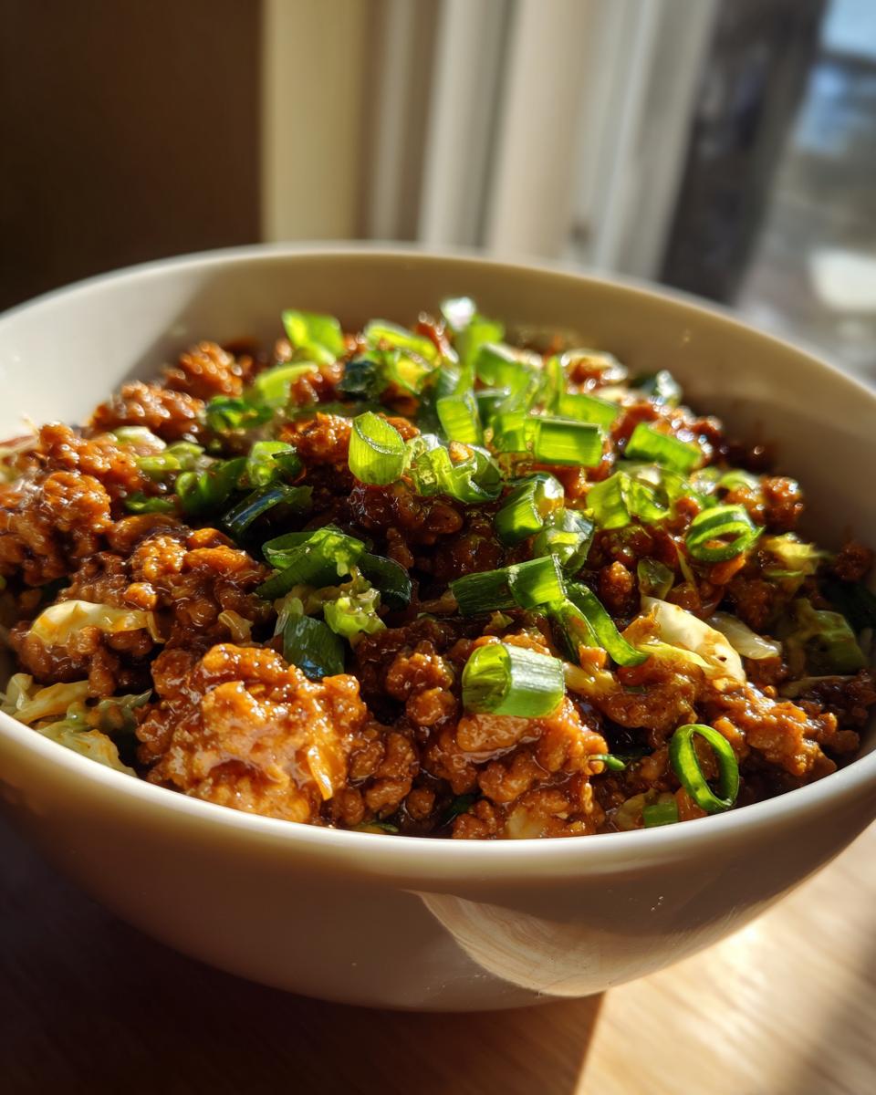 Close-up of a bowl filled with Irresistible Egg Roll In A Bowl, topped with fresh green onions.