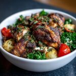 Close-up of Irresistible Greek Chicken Bowls featuring seasoned chicken, roasted potatoes, kale, and cherry tomatoes.
