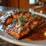 Two glistening fillets of Irresistible Honey Garlic Salmon Recipe, topped with fresh parsley and served in a rich glaze.