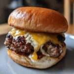 A close-up of an irresistible smash burger with a juicy, browned patty, melted cheddar cheese, and a soft bun.