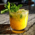 A refreshing Pineapple Chia Seed Tropical Mocktail in a glass, garnished with fresh mint leaves and ice.