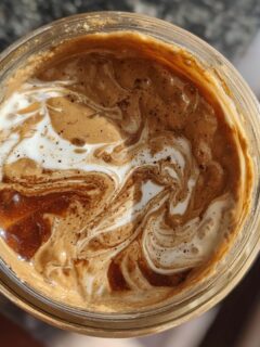 Overhead view of Protein Peanut Butter Jelly Overnight Oats in a jar, with swirls of cream and peanut butter.