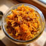 Close-up of Spiced Carrot Cake Overnight Oats in a glass jar, topped with shredded carrots and spices.