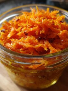 Close-up of Spiced Carrot Cake Overnight Oats mixture in a glass jar, showing shredded carrots and spices.