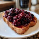 Close-up of two slices of toast topped with juicy roasted blackberries and syrup for a vegan breakfast.