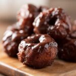 Close-up of freshly made vegan chocolate donut holes, glistening with chocolate glaze.
