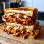 Close-up of a stacked Baked BBQ Chicken Grilled Cheese Dairy Free sandwich showing melted cheese and saucy chicken filling.